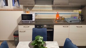 A modern kitchen with a microwave, toaster, sink, and stove. There is a trash bin and a table with a plant. - "Waldhaus" in der Nähe des Strandes by Interhome (Rab/Kampor)