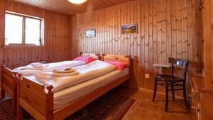 A wooden-paneled room with two beds, a chair, and a window. - Chalet Chiara by Interhome (Casaccia)