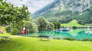 A lakeside view with a bench, picnic table, and boats docked.