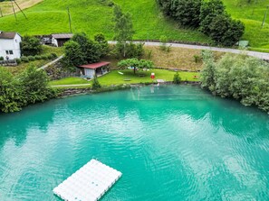 A clear view of a swimming pool with a dock, surrounded by greenery and a small building. - Chalet Oasis by Interhome (Bürglen OW)