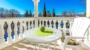 A balcony with a white metal table and chairs, a green cushion, and a view of trees and mountains. - "Vila Chiara" mit Pool by Interhome (Crikvenica/Dramalj)