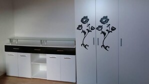 A room with a white wardrobe featuring floral decals, a black countertop with drawers, and a glass shelf.