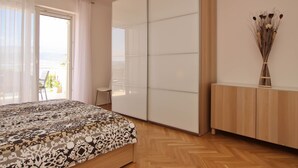 Un dormitorio con cama, armario corredero, una silla y vistas al exterior.