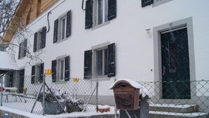 A white building with black shutters, a mailbox, and a number 12 door. - "Ferme d' Alma" by Interhome (Seleute)