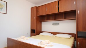 A bedroom with a wooden bed, two pillows, and a yellow bedspread. - Apartment Andjela by Interhome (Krk/Šilo)