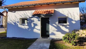 A single-story house with a tiled roof, a black door, and two windows on the side. - la maisonnette by Interhome (Saignelegier)