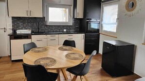 A compact kitchen with a round wooden table, black chairs, and a black refrigerator. - la maisonnette by Interhome (Saignelegier)