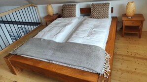A wooden bed with white bedding and a grey throw blanket, two woven nightstands, and a wooden railing. - la maisonnette by Interhome (Saignelegier)