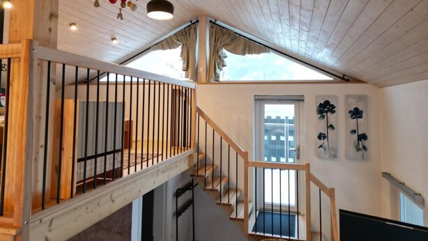 A wooden interior with a staircase, a ceiling with hanging decorations, and a window with a view. - la maisonnette by Interhome (Saignelegier)