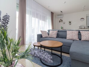 A modern living room with a grey sofa, two round coffee tables, and decorative pillows. - Wohnung Vita Mare mit Pool - Agentur TA Leut by Interhome (Privlaka)