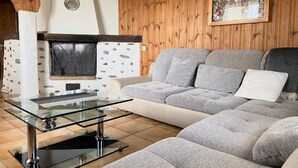A cozy living room with a stone fireplace, a glass coffee table, and a grey sofa.