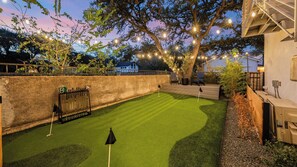 Ein gepflegter Golfplatz mit Putting Green, Holzzaun und Steinmauer.