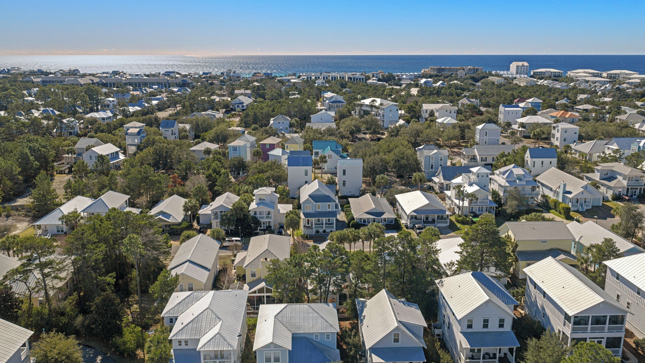 A coastal residential area with houses, trees, and a view of the ocean.
