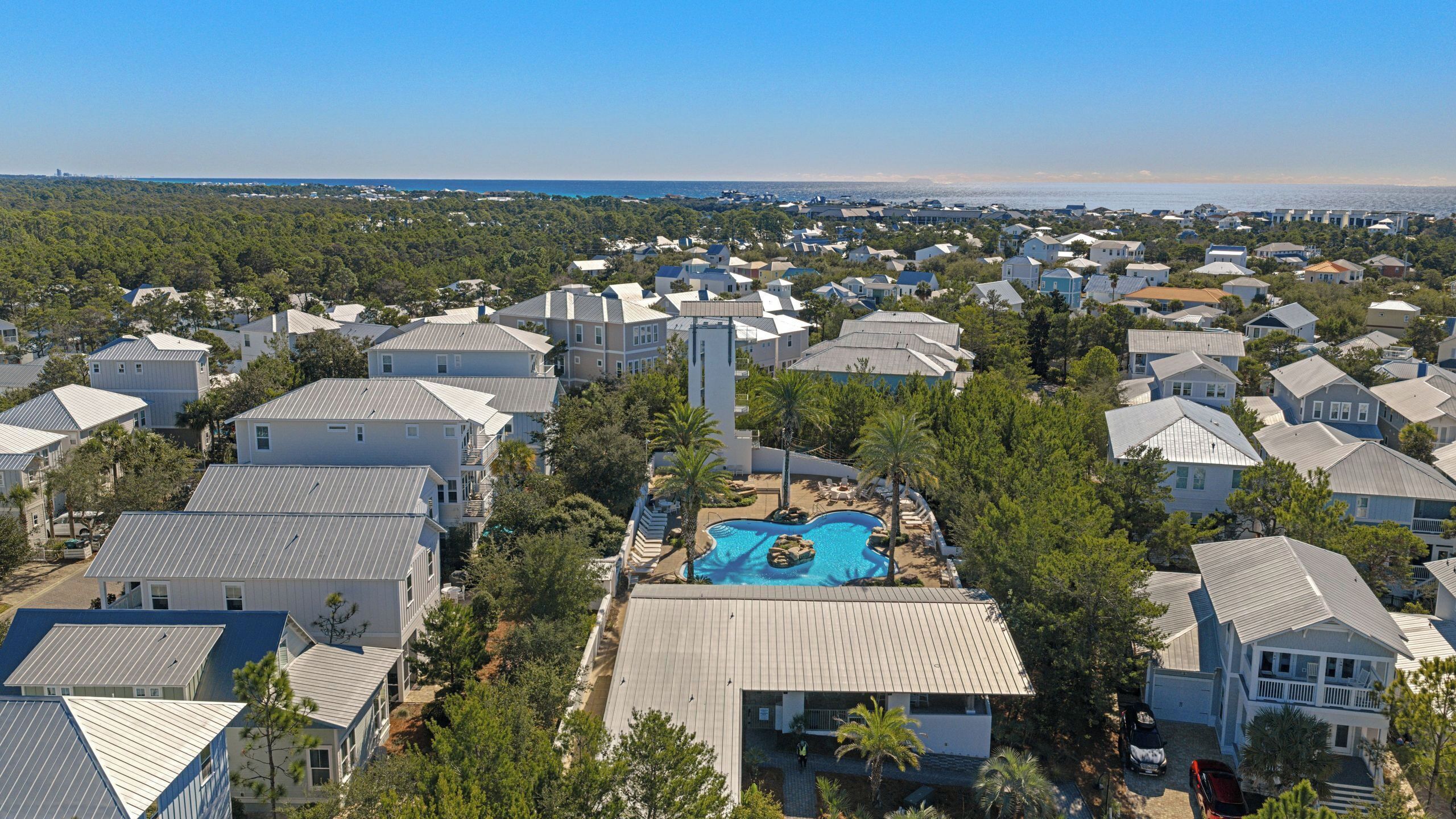 A residential area with houses, a swimming pool, and a view of the ocean.