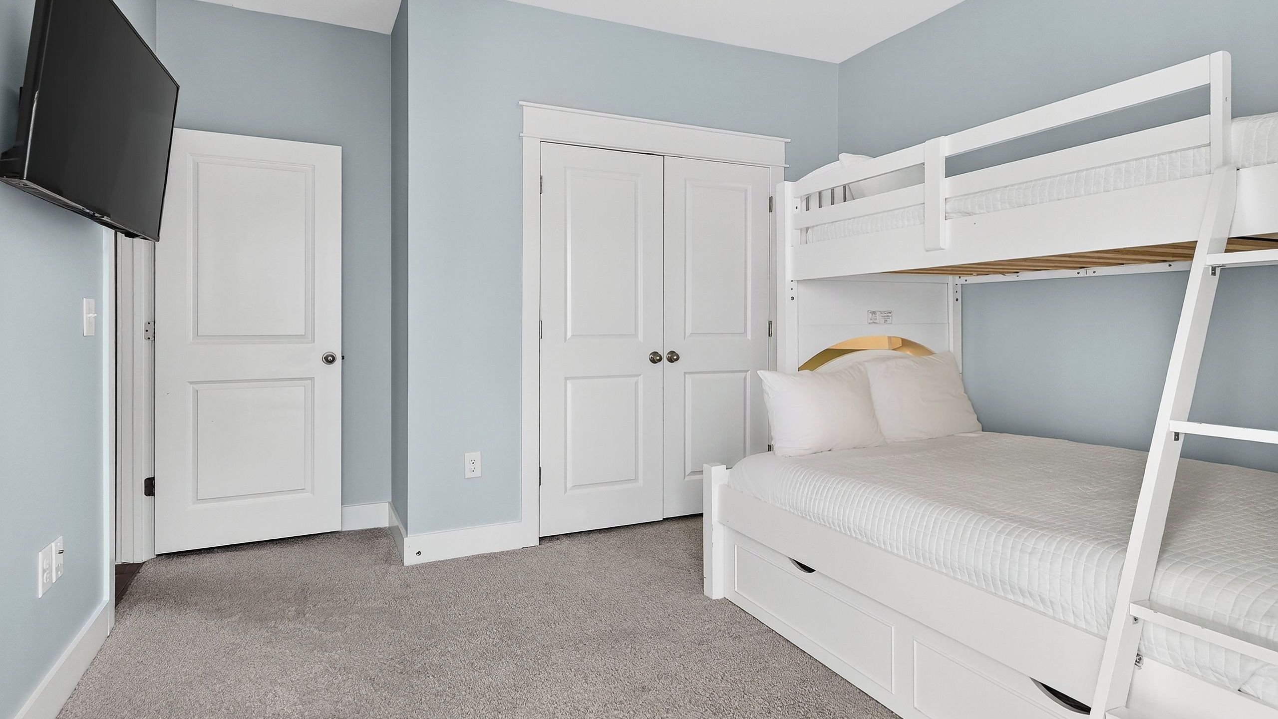 Ein Zimmer mit Etagenbett, Kleiderschrank und Fernseher.