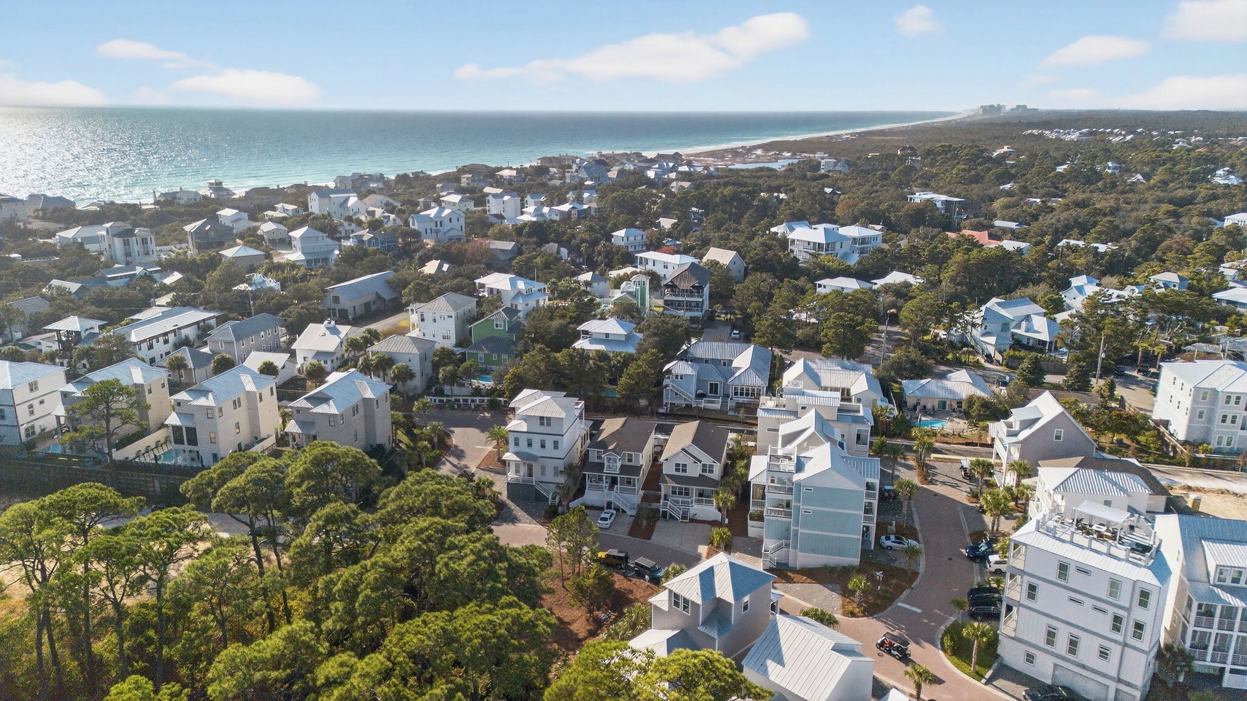 A coastal residential area with houses, roads, and a beach in the background.