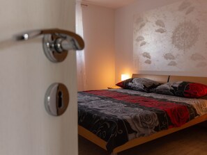Ein Schlafzimmer mit einem Bett, einem Nachttisch und einer Wand mit floralem Muster.