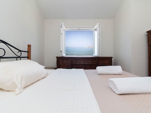 Ein Schlafzimmer mit Bett, Kommode und Meerblick.