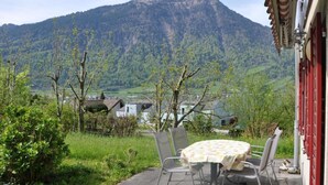 Une terrasse avec une table et des chaises, offrant une vue sur un paysage montagneux.