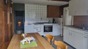 Une cuisine compacte avec des meubles blancs, une table à manger en bois et un four encastré.