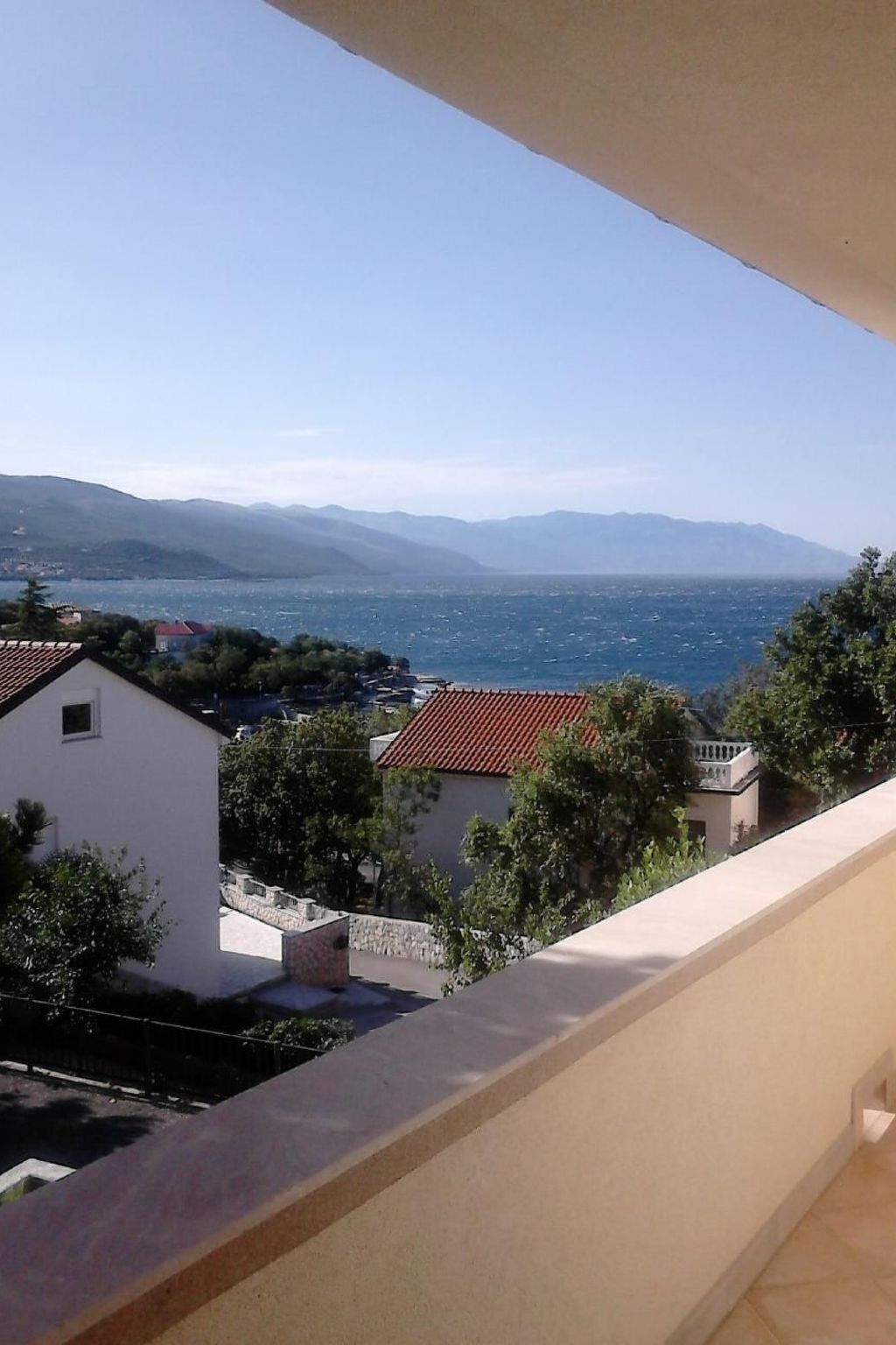 Un balcón con vistas a un pueblo costero y montañas.