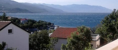 Un balcón con vistas a un pueblo costero y montañas.
