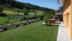 Un immeuble résidentiel doté d’un balcon donnant sur un paysage verdoyant et des collines.