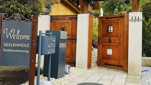 Indgang til en trælodge med et skilt, der siger "Welcome SEELENHOLZ Ferienwohnung", og en port med en plade med nummeret "331".