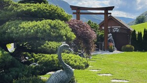 En traditionel japansk have med en torii-port, frodig vegetation og en stor fuglestatue.