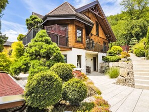 A two-story wooden house with a balcony, surrounded by well-maintained gardens and a stone pathway. - Seelenholz by Interhome (Herbetswil)