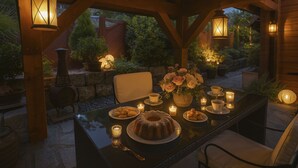 Et udendørs spiseområde med et bord til to, omgivet af træbjælker og stenvægge.