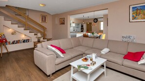 Ein modernes Wohnzimmer mit einem beigefarbenen Sofa, einem weißen Couchtisch und einer Treppe.