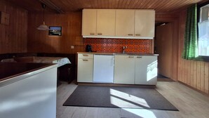 A compact kitchen with wooden cabinets, a built-in oven, and a small countertop. - Stöckli EG by Interhome (Bowil)