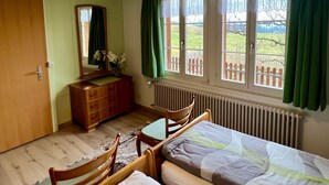 A bedroom with a bed, a dresser, a mirror, and a window with curtains. - Chalet Hulda by Interhome (Heimenschwand)