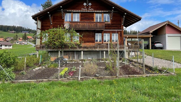 A chalet-style wooden building with a balcony, a covered porch, and a small garden area. - Chalet Hulda by Interhome (Heimenschwand)