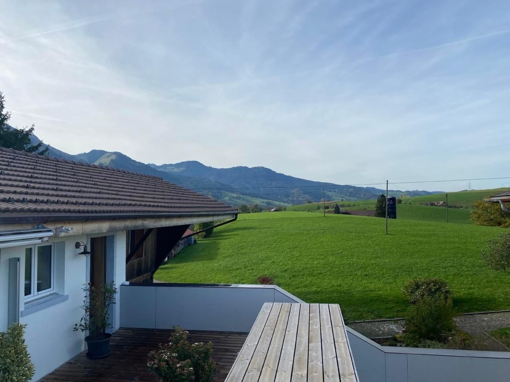 Ein Haus mit Ziegeldach, Holzterrasse und Rasengarten.