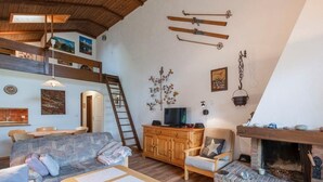 Un saló menjador acollidor d'estil loft amb un llit de fusta, una xemeneia i zona de dinar.