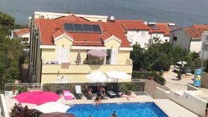 Ett hotell med en swimmingpool, rödfärgade tak och utsikt över havet.