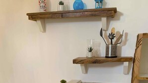 A kitchen with a stainless steel sink, a wooden shelf above it, and a tiled backsplash. - Biancostuni81, Le Piccole Case Bianche (Ostuni)