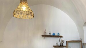 A kitchen with a hanging light fixture, a white countertop, and a wooden shelf with kitchenware. - Biancostuni81, Le Piccole Case Bianche (Ostuni)
