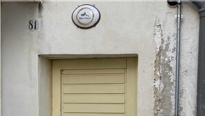 A beige door with horizontal slats, a metal utility box, and a sign above the door. - Biancostuni81, Le Piccole Case Bianche (Ostuni)