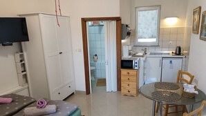 A compact hotel room with a bed, a small kitchenette, a dining area, and a TV. - Budget-Studio für zwei Personen by Interhome (Biograd na Moru)