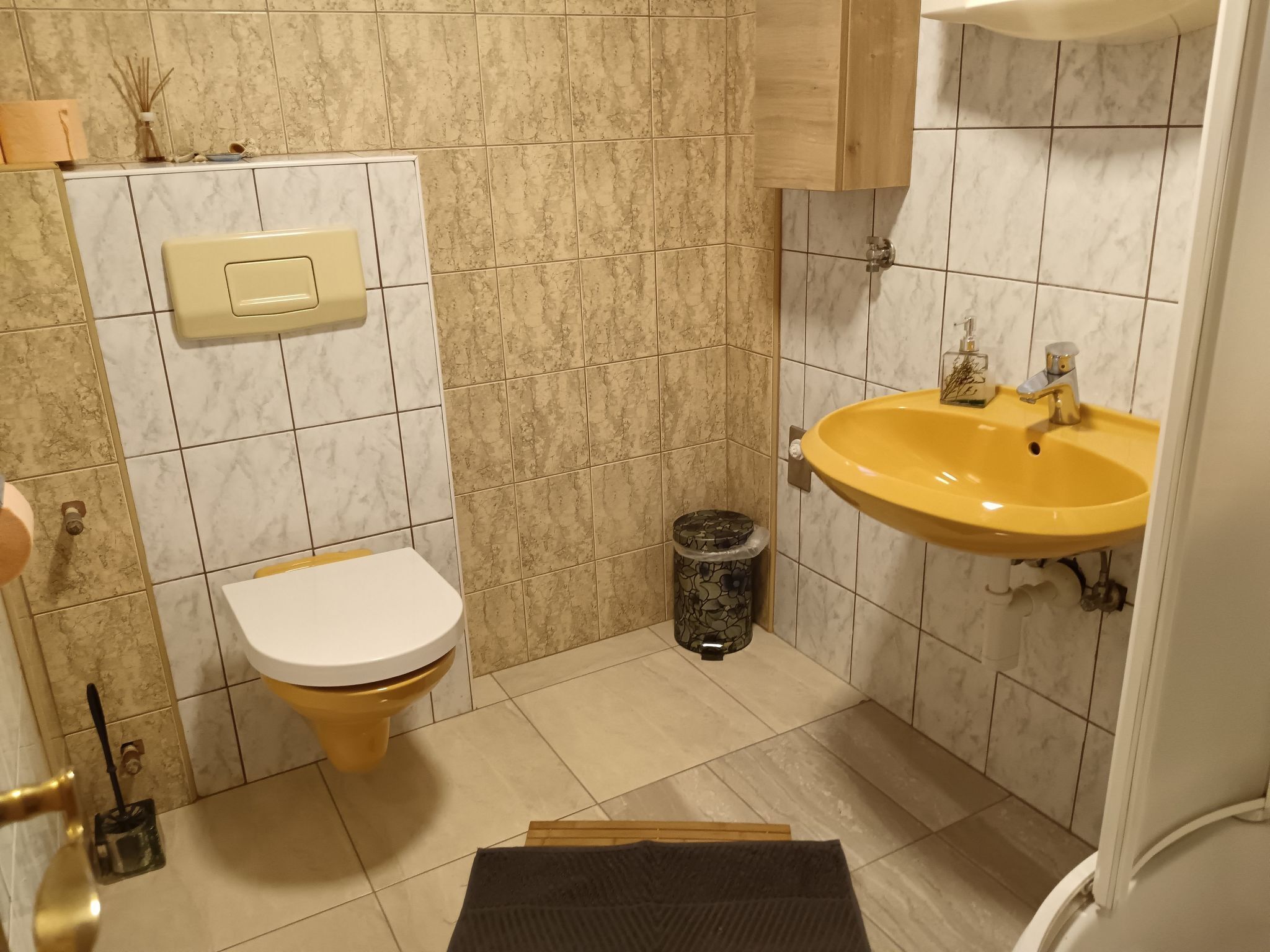 A bathroom with a toilet, sink, and trash bin.