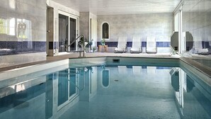 Una piscina con sillas de descanso y zona para tomar el sol.