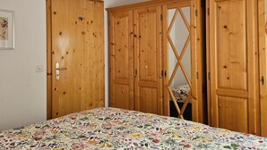 Un dormitorio con una colcha de estampado floral, armarios de madera y un ventilador de techo.