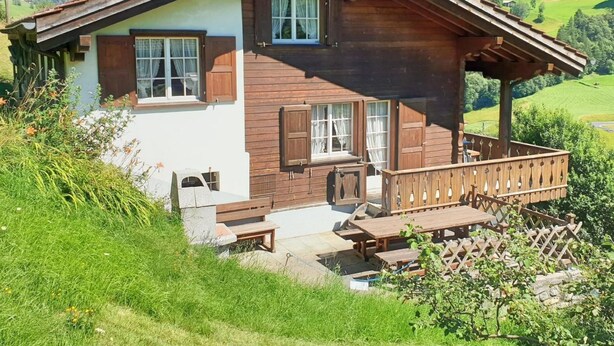 Eine Chalet mit Holzausbau, einem Balkon und einem Kamin aus Stein.