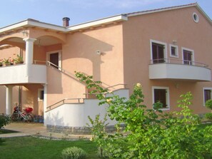 Ein zweigeschossiges Haus mit Balkon, Treppe und Garten.