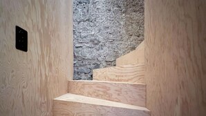 Una escala de fusta amb un mur de pedra al fons.