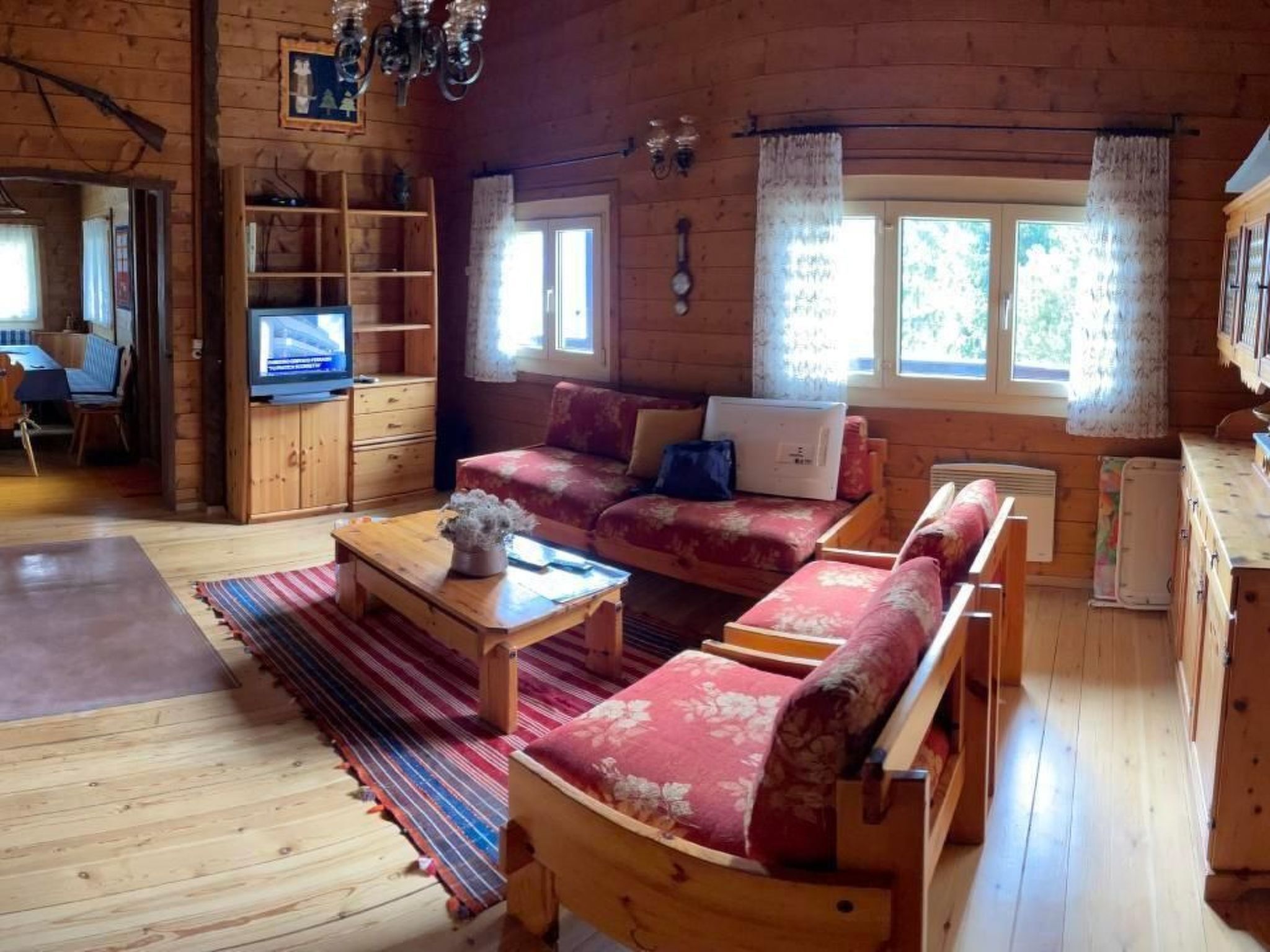 Ein gemütliches Blockhaus-Interieur mit einer Couch, einem Couchtisch, einem Fernseher und einem Bücherregal.