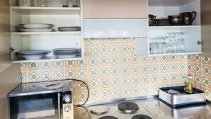 Una cocina con estufa, horno y diferentes utensilios de cocina en estantes.